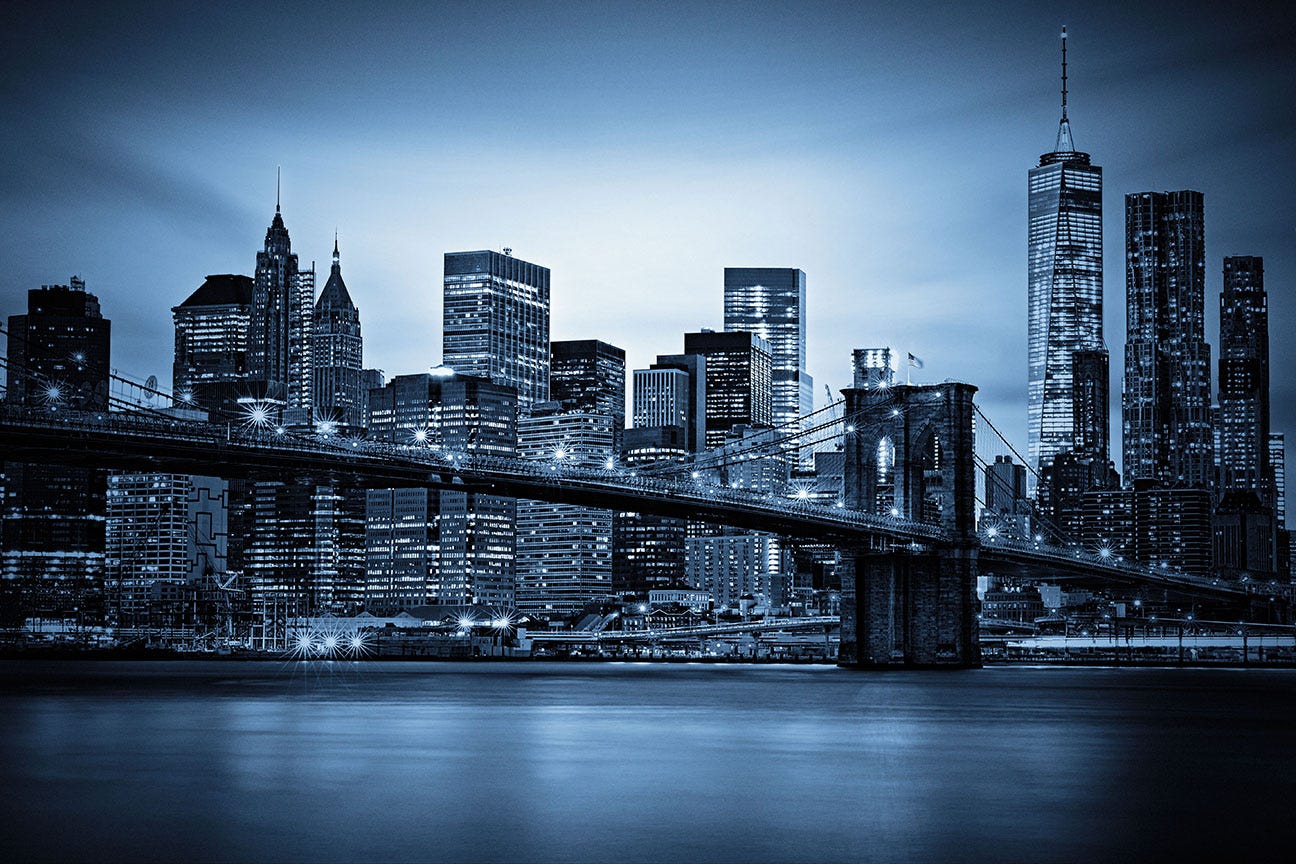 Brooklyn Bridge at and the Lower Manhattan skyline under a purple sunset